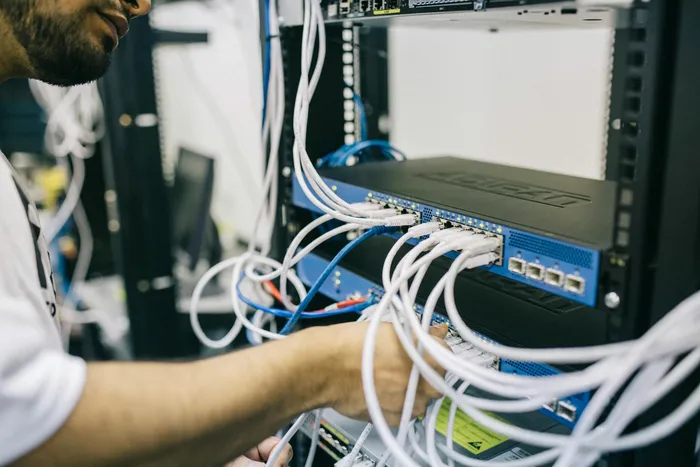 A technician managing network cables and equipment in a server rack, ensuring proper connections for optimal performance.
