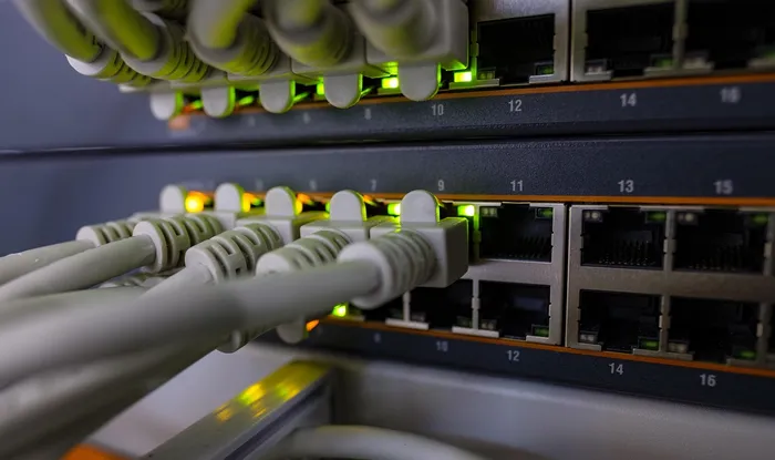 Close-up of a network switch with Ethernet cables connected, displaying green LED indicators, indicating active connections.